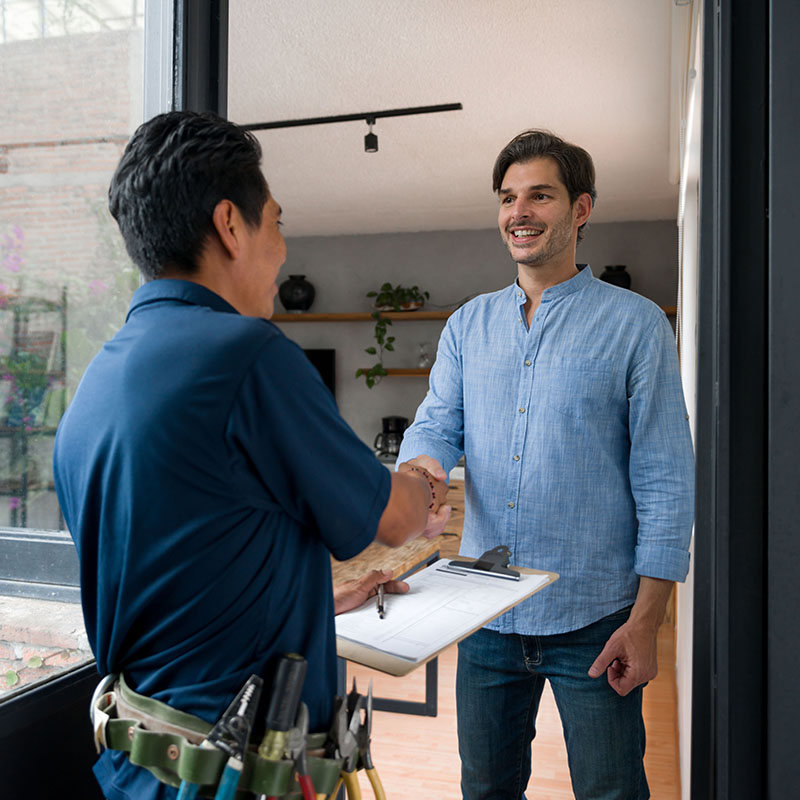 Electrician greeting a client with a handshake at the door of his house