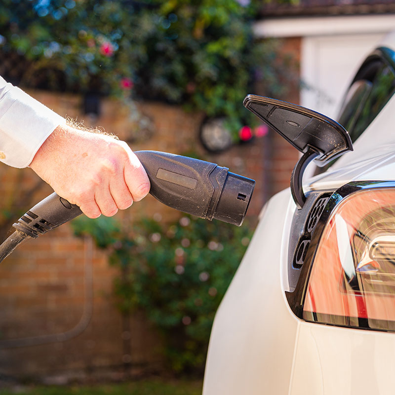 Man charging electric car at home