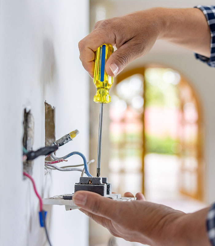 Electrician installing a power outlet while remodeling a house