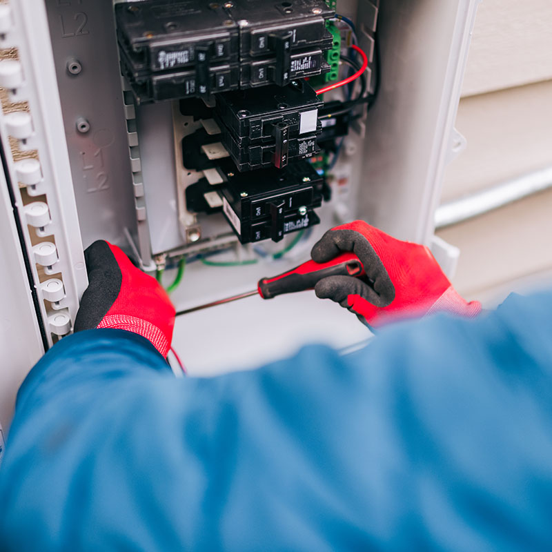 A Solar Energy Technician works on wiring and connections on an electrical breaker box